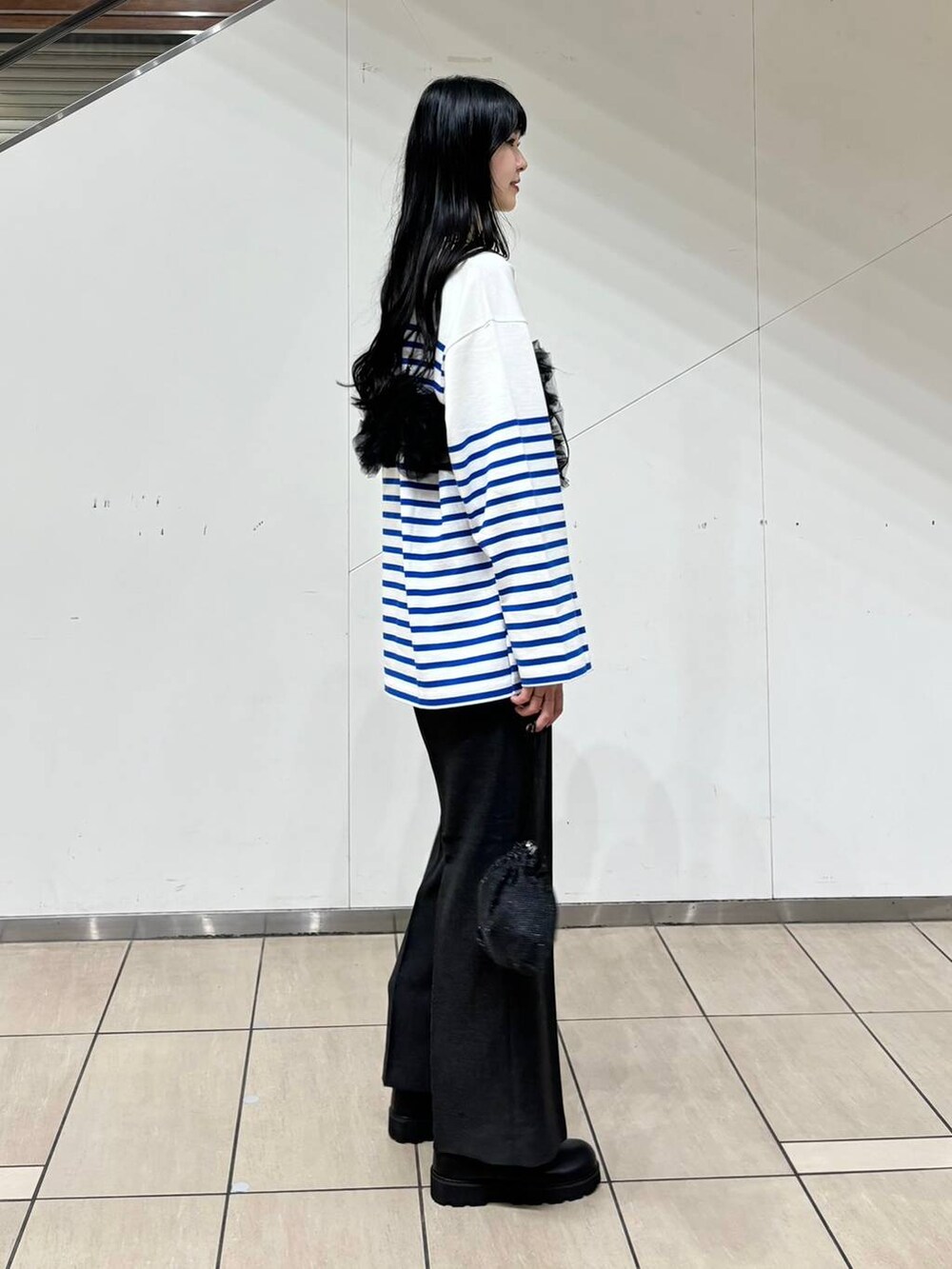 グレー系のスラックス、ブラック系のブーツ、ブラック系のショルダーバッグを着用したレディースの秋コーディネートの2枚目の写真