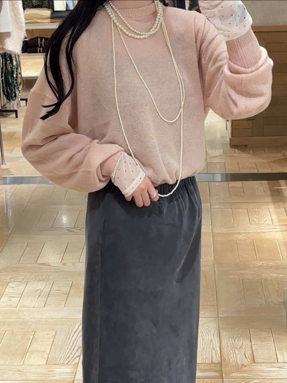 グレー系のスカート、ピンク系のニット/セーター、ホワイト系のTシャツ/カットソーを着用したレディースの秋コーディネートの3枚目の写真