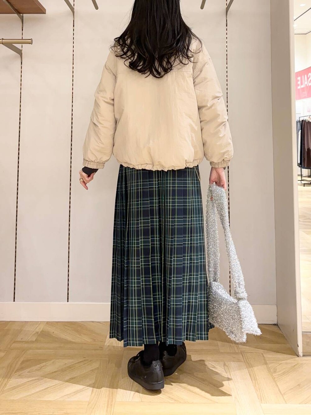 シルバー系のショルダーバッグ、ベージュ系のブルゾン、ブルー系のスカートを着用したレディースの冬コーディネートの3枚目の写真