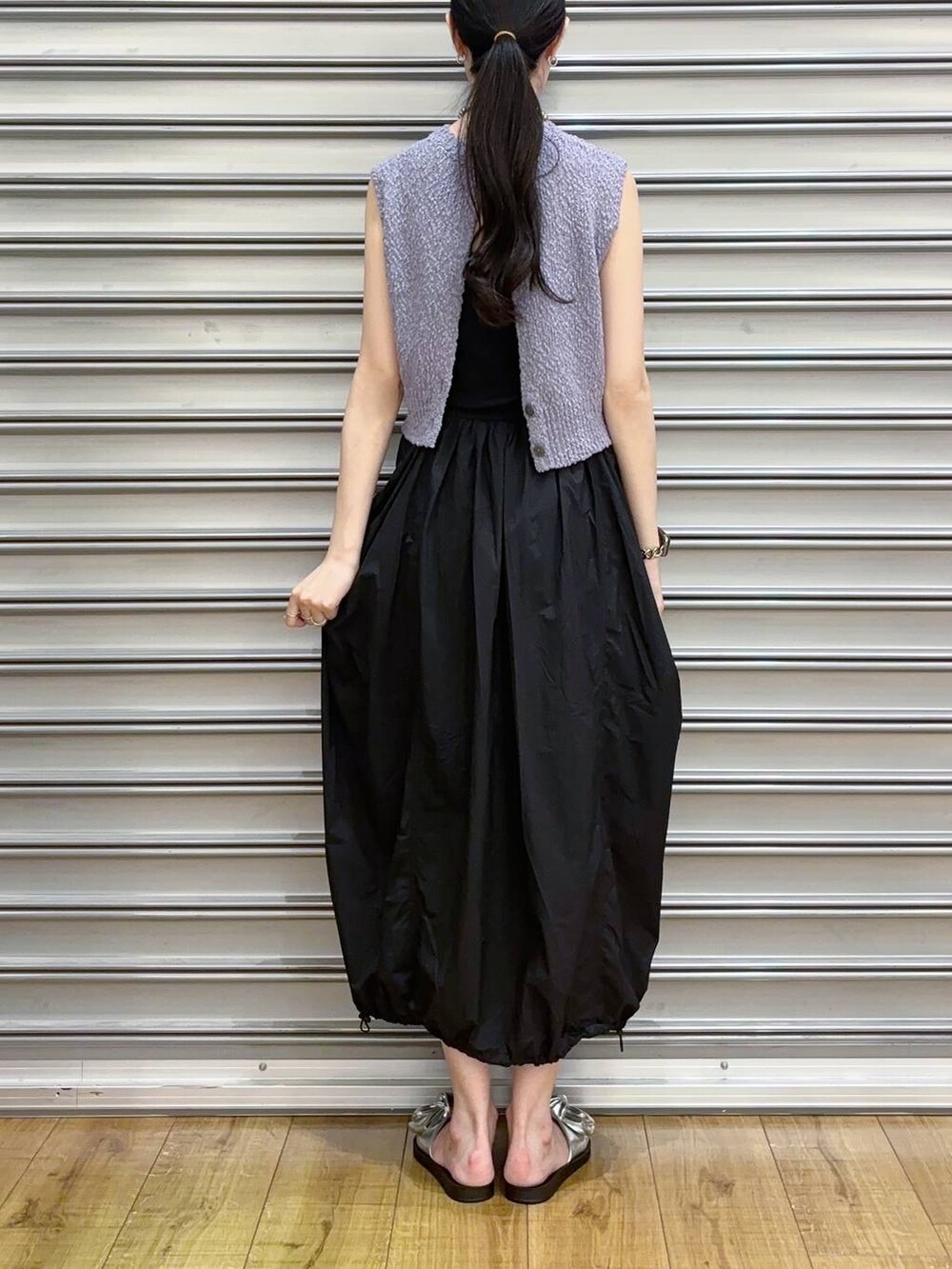 シルバー系のサンダル、ブラック系のスカート、パープル系のベストを着用したレディースの夏コーディネートの3枚目の写真