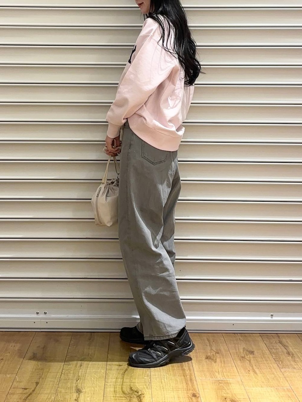 ピンク系のスウェット、グレー系のデニムパンツ、ホワイト系のショルダーバッグを着用したレディースの冬コーディネートの2枚目の写真