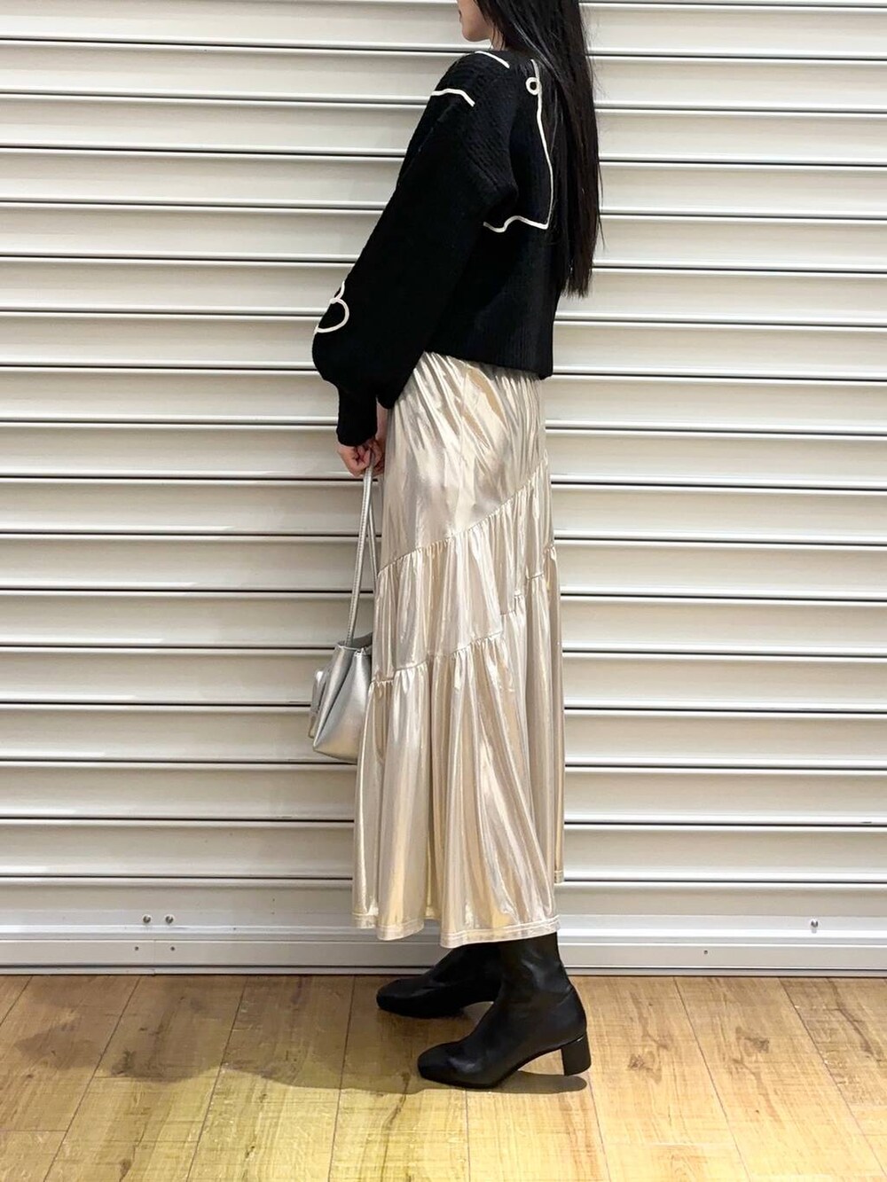 シルバー系のショルダーバッグ、ブラック系のブーツ、ホワイト系のスカートを着用したレディースの冬コーディネートの2枚目の写真