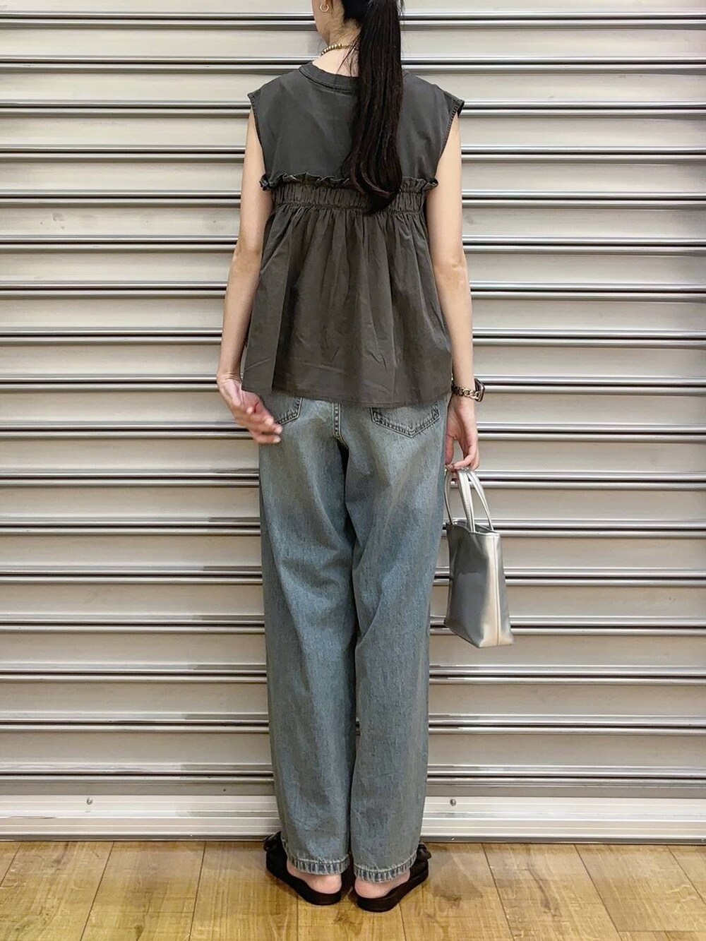 ブルー系のデニムパンツ、シルバー系のショルダーバッグ、ブラック系のサンダルを着用したレディースの夏コーディネートの3枚目の写真