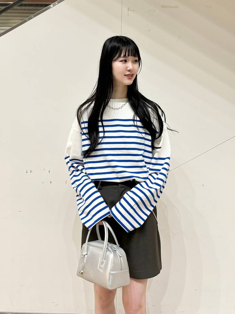 ブラック系のブーツ、シルバー系のボストンバッグ、グレー系のその他パンツを着用したレディースの秋コーディネートの3枚目の写真