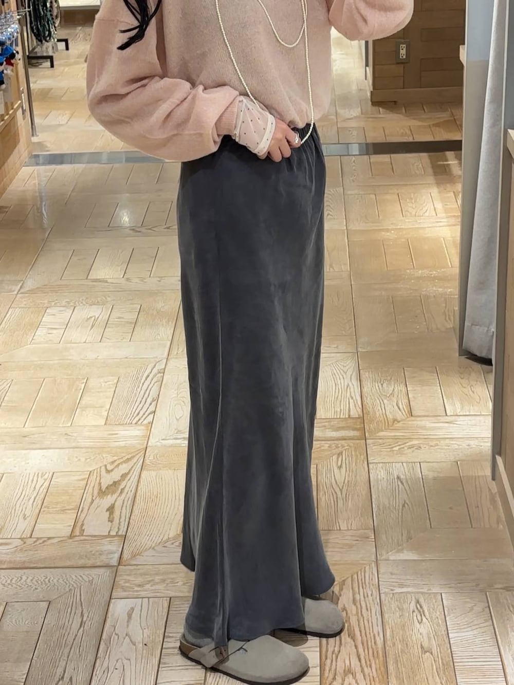 グレー系のスカート、ピンク系のニット/セーター、ホワイト系のTシャツ/カットソーを着用したレディースの秋コーディネートの2枚目の写真