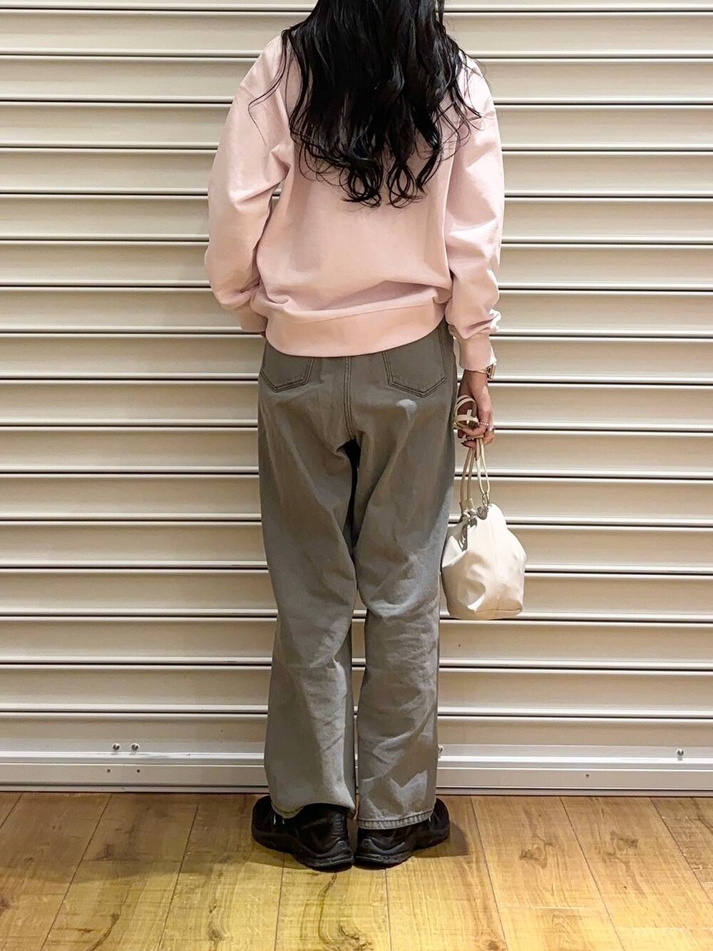 ピンク系のスウェット、グレー系のデニムパンツ、ホワイト系のショルダーバッグを着用したレディースの冬コーディネートの3枚目の写真