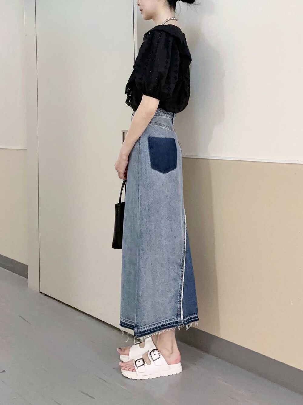 ブラック系のショルダーバッグ、ブルー系のスカート、ホワイト系のサンダルを着用したレディースの夏コーディネートの2枚目の写真