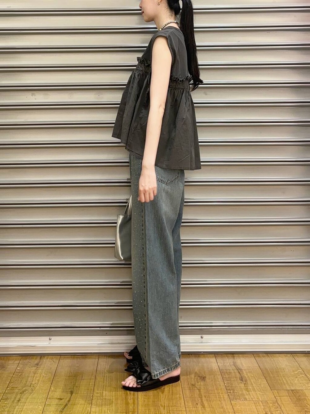 ブルー系のデニムパンツ、シルバー系のショルダーバッグ、ブラック系のサンダルを着用したレディースの夏コーディネートの2枚目の写真