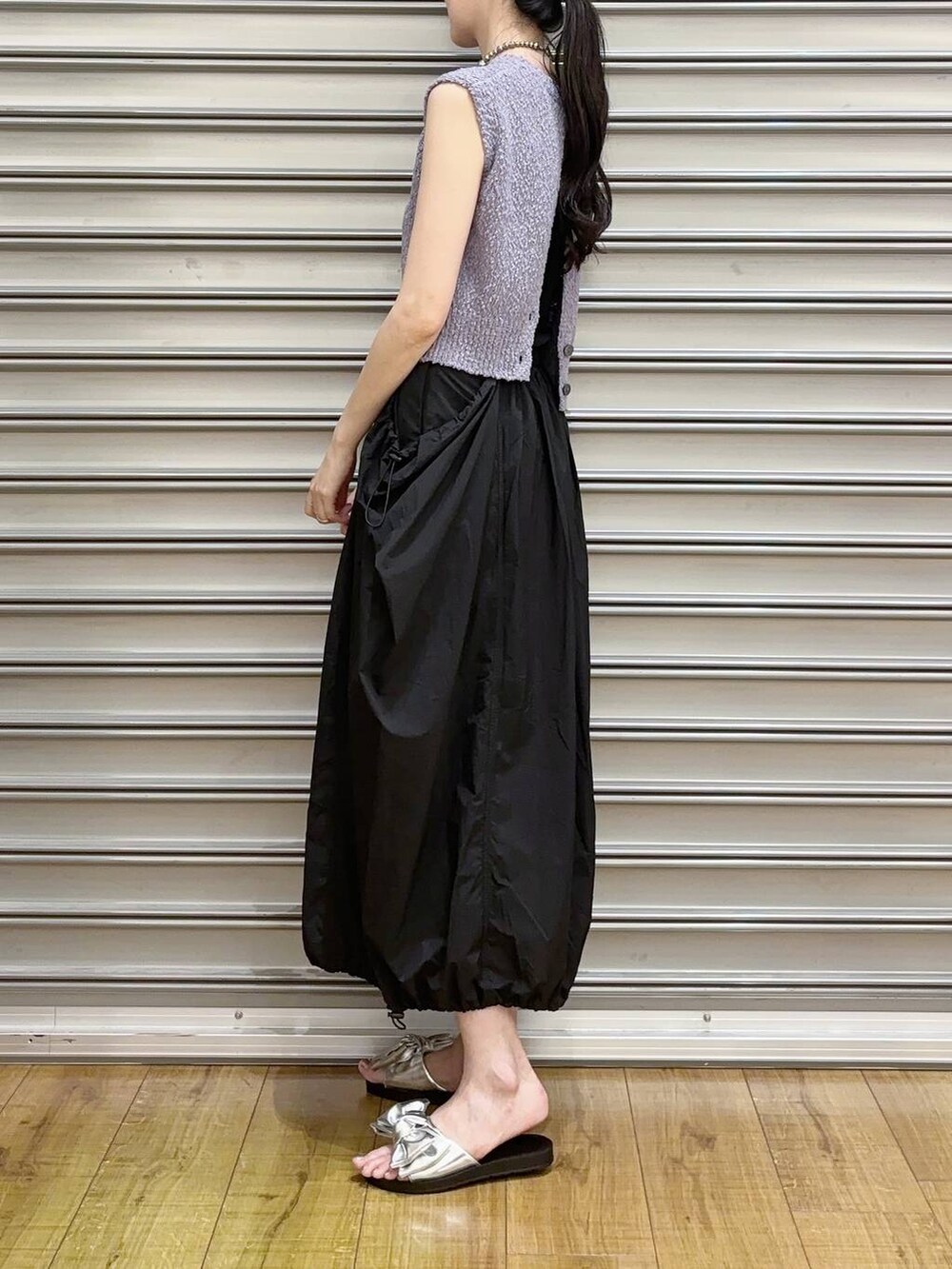 シルバー系のサンダル、ブラック系のスカート、パープル系のベストを着用したレディースの夏コーディネートの2枚目の写真