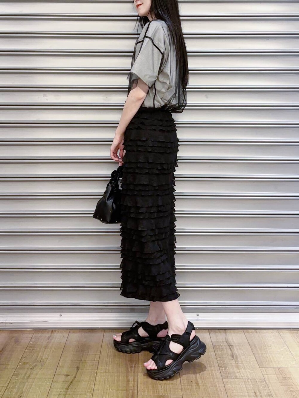 ブラック系のハンドバッグ、ブラック系のスカート、ブラック系のサンダルを着用したレディースの夏コーディネートの2枚目の写真