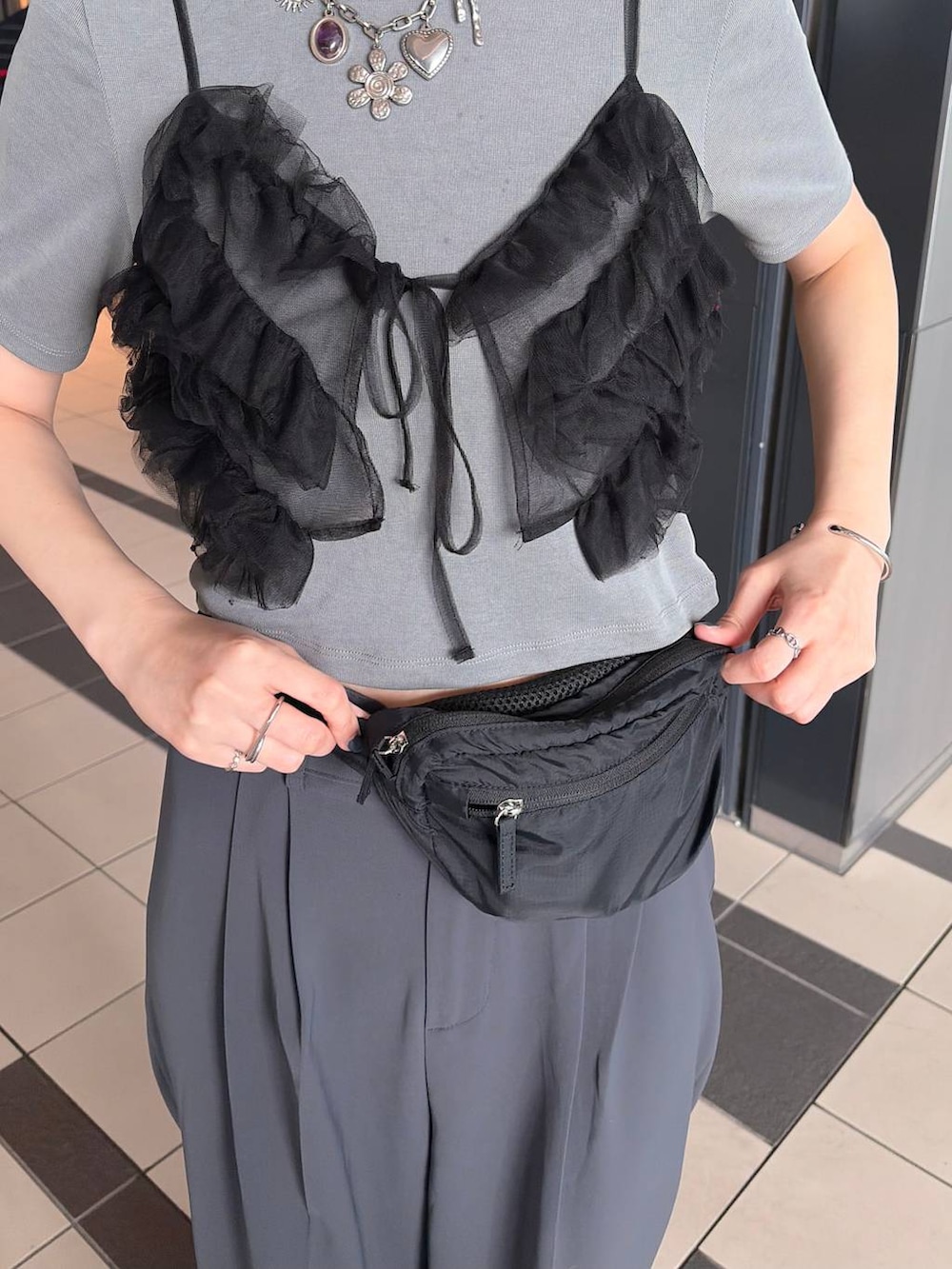 ブラック系のボディバッグ/ウエストポーチ、グレー系のTシャツ/カットソーを着用したレディースの春コーディネートの2枚目の写真