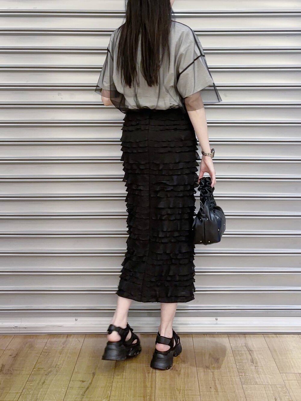 ブラック系のハンドバッグ、ブラック系のスカート、ブラック系のサンダルを着用したレディースの夏コーディネートの3枚目の写真