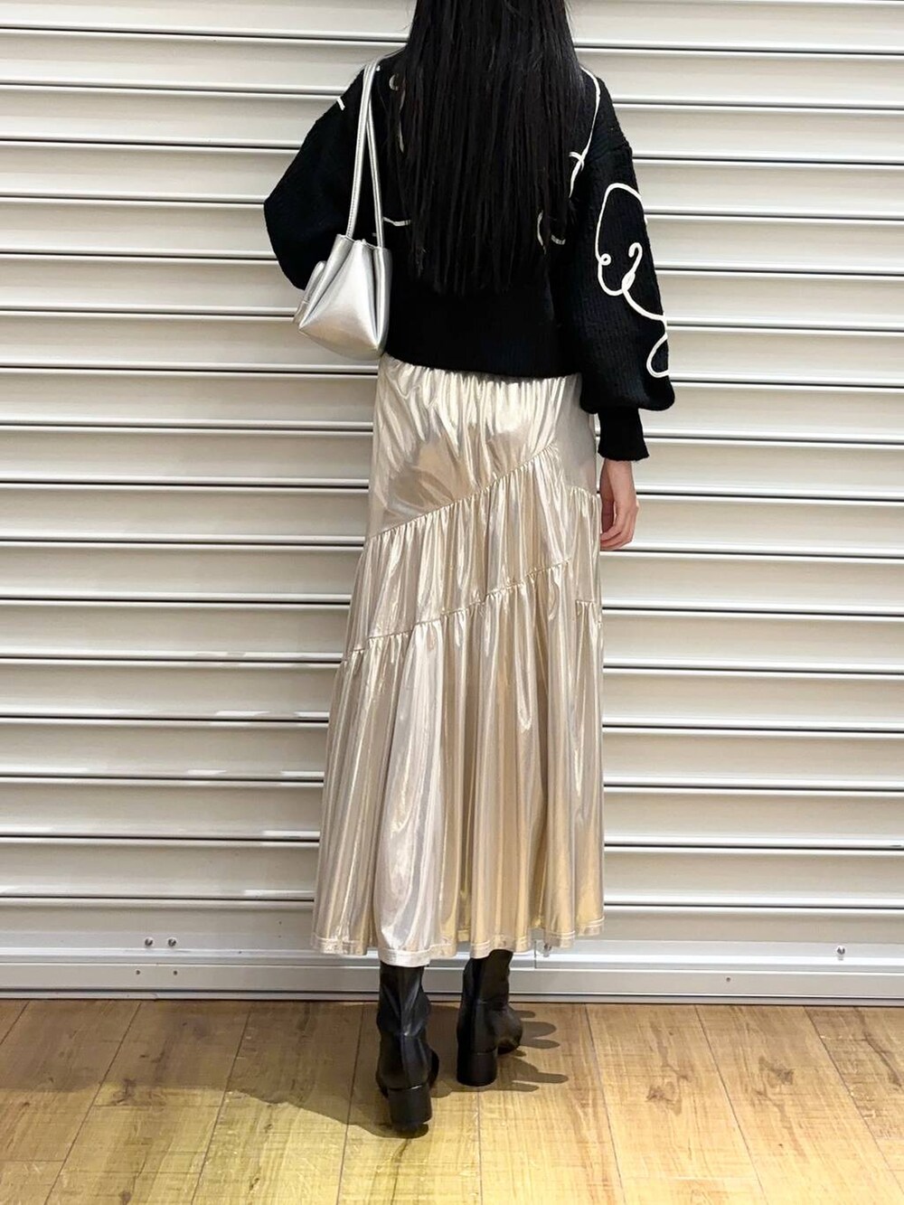 シルバー系のショルダーバッグ、ブラック系のブーツ、ホワイト系のスカートを着用したレディースの冬コーディネートの3枚目の写真