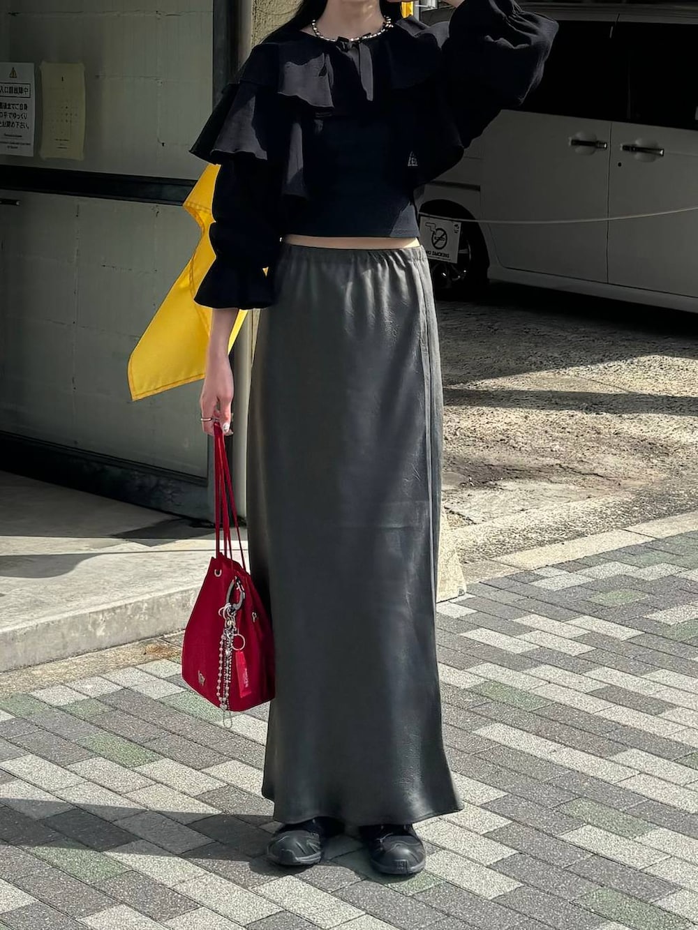 レッド系のハンドバッグ、ブルー系のキャップを着用したレディースの春コーディネートの2枚目の写真