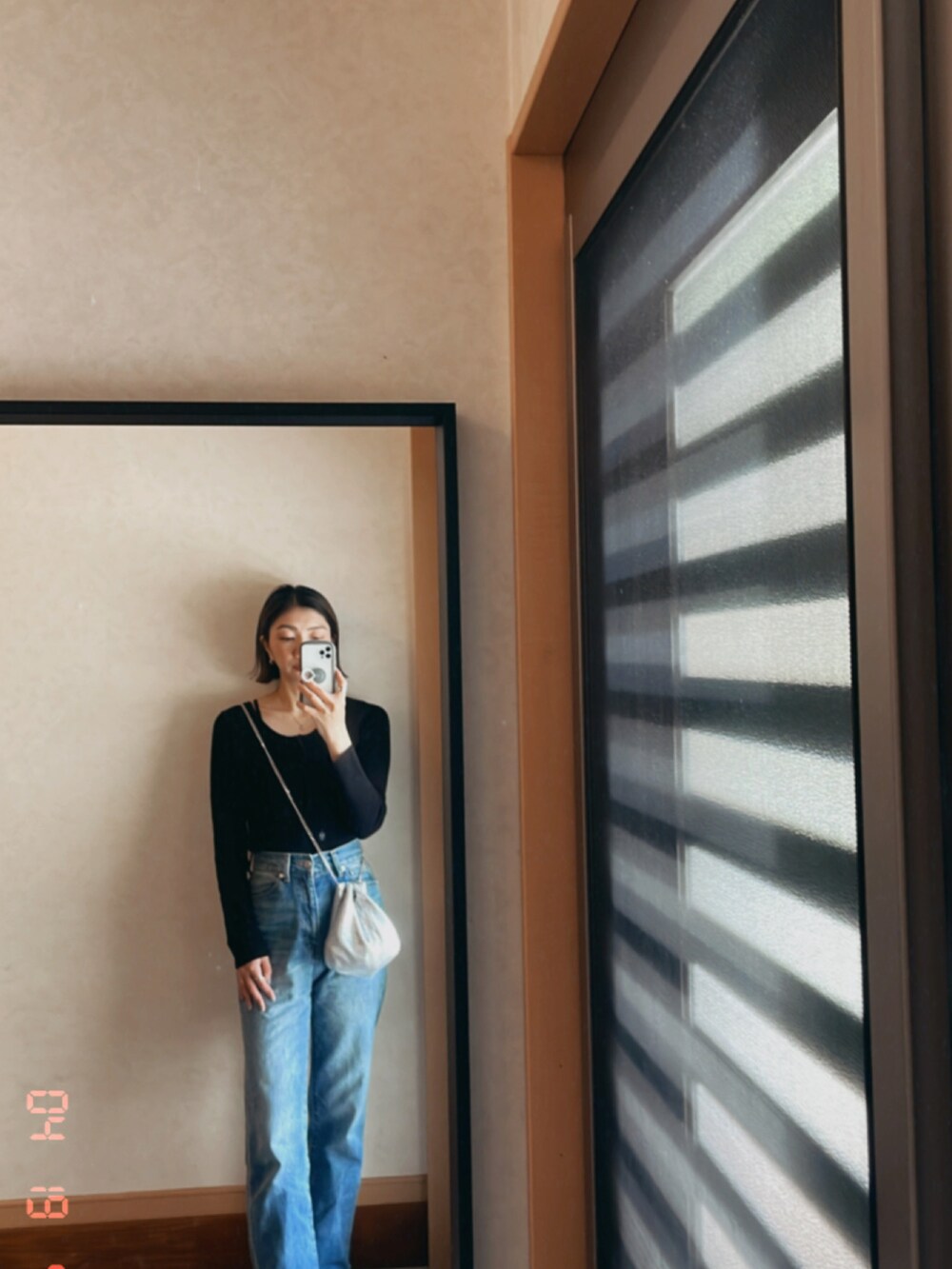 ブラック系のトップス、ブルー系のデニムパンツ、シルバー系のショルダーバッグを着用したレディースの春コーディネートの2枚目の写真