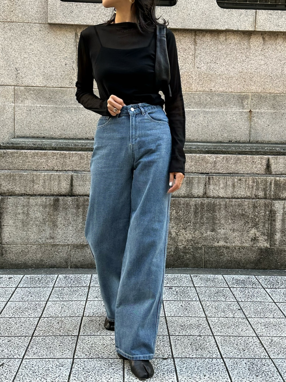 ブラック系のTシャツ/カットソー、ブルー系のデニムパンツ、ブラック系のハンドバッグを着用したレディースの秋コーディネートの2枚目の写真