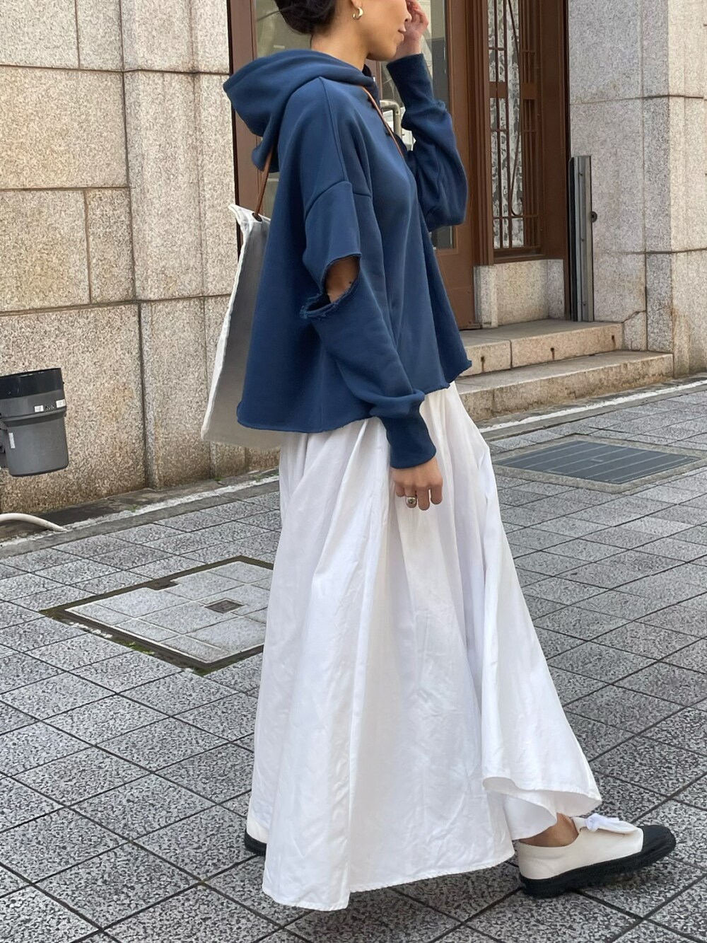 ブルー系のスウェット、ホワイト系のスニーカー、ホワイト系のメッセンジャーバッグを着用したレディースの春コーディネートの2枚目の写真