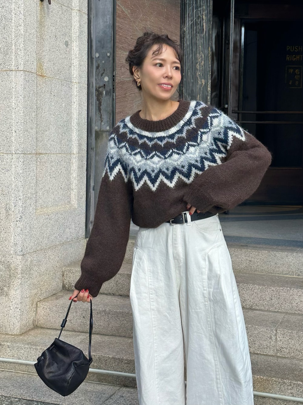 ブラウン系のニット/セーター、ホワイト系のデニムパンツ、ブラウン系のモカシン/デッキシューズを着用したレディースの秋コーディネートの2枚目の写真