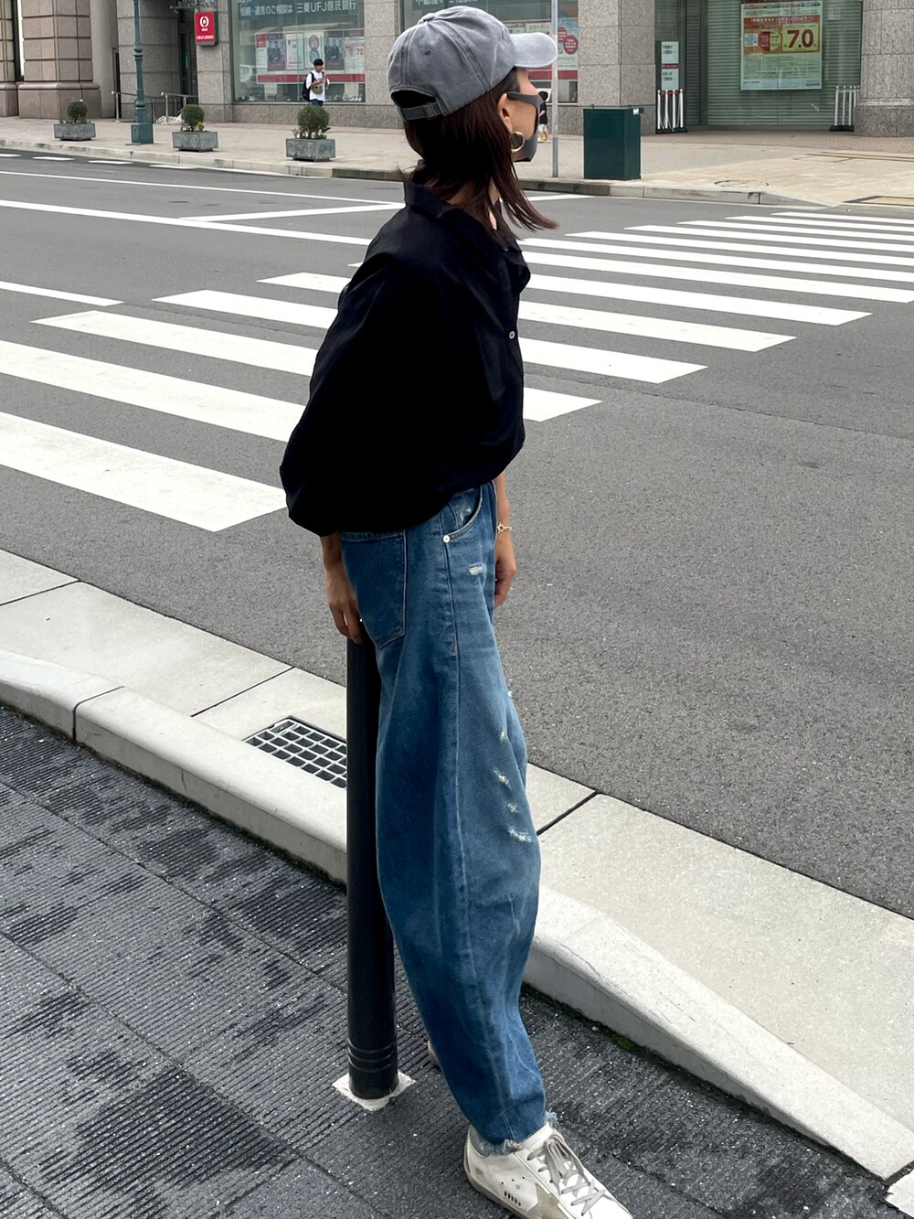 ブルー系のデニムパンツ、ホワイト系のスニーカー、ブラック系のボディバッグ/ウエストポーチを着用したレディースの秋コーディネートの2枚目の写真