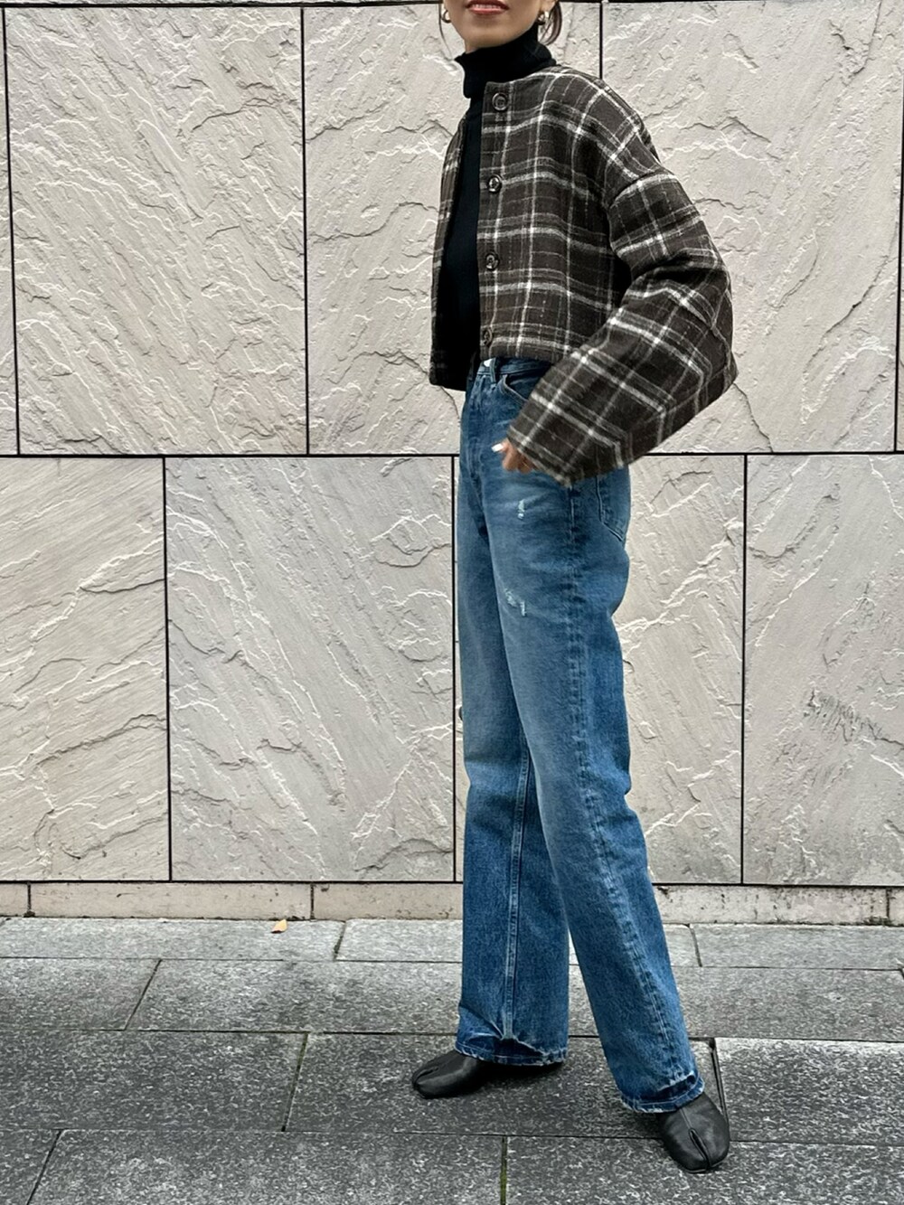 ブラウン系のノーカラージャケット、ブルー系のデニムパンツ、ブラック系のブーツを着用したレディースの冬コーディネートの2枚目の写真