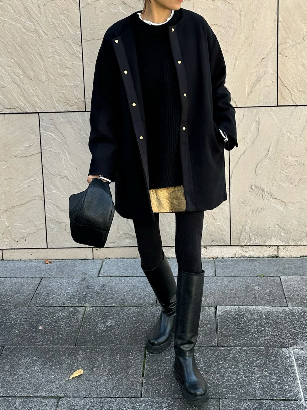 ブラック系のノーカラーコート、ブラック系のブーツ、ブラック系のハンドバッグを着用したレディースの秋コーディネートの2枚目の写真