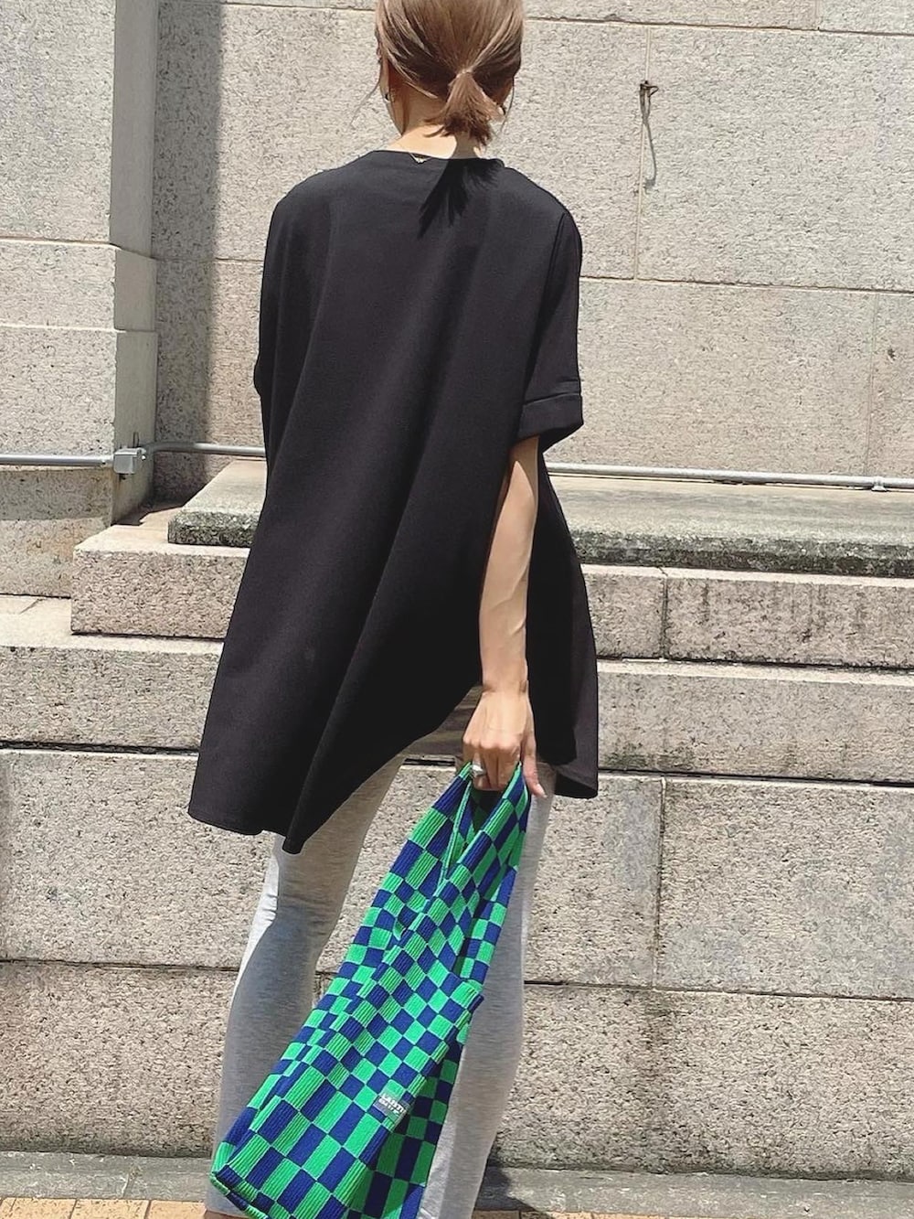 ブラック系のTシャツ/カットソー、グリーン系のトートバッグを着用したレディースの春コーディネートの2枚目の写真