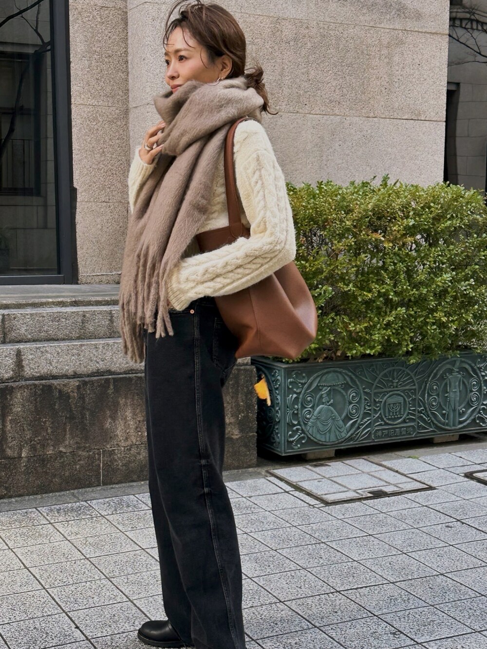 ベージュ系のニット/セーター、ブラウン系のトートバッグ、ブラック系のデニムパンツを着用したレディースの冬コーディネートの2枚目の写真