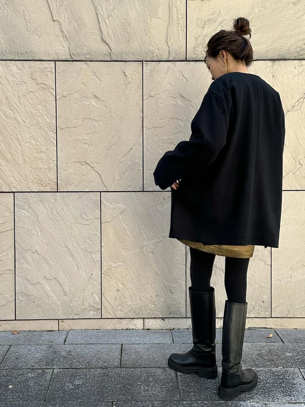 ブラック系のノーカラーコート、ブラック系のブーツ、ブラック系のハンドバッグを着用したレディースの秋コーディネートの3枚目の写真