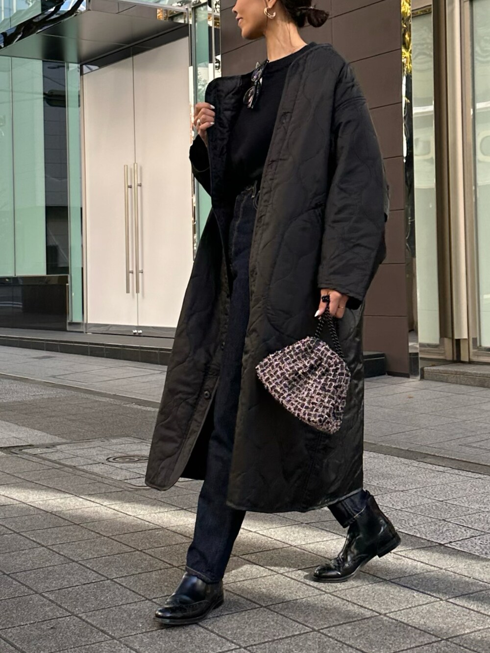 ブラック系のノーカラーコート、ブルー系のデニムパンツを着用したレディースの秋コーディネートの2枚目の写真