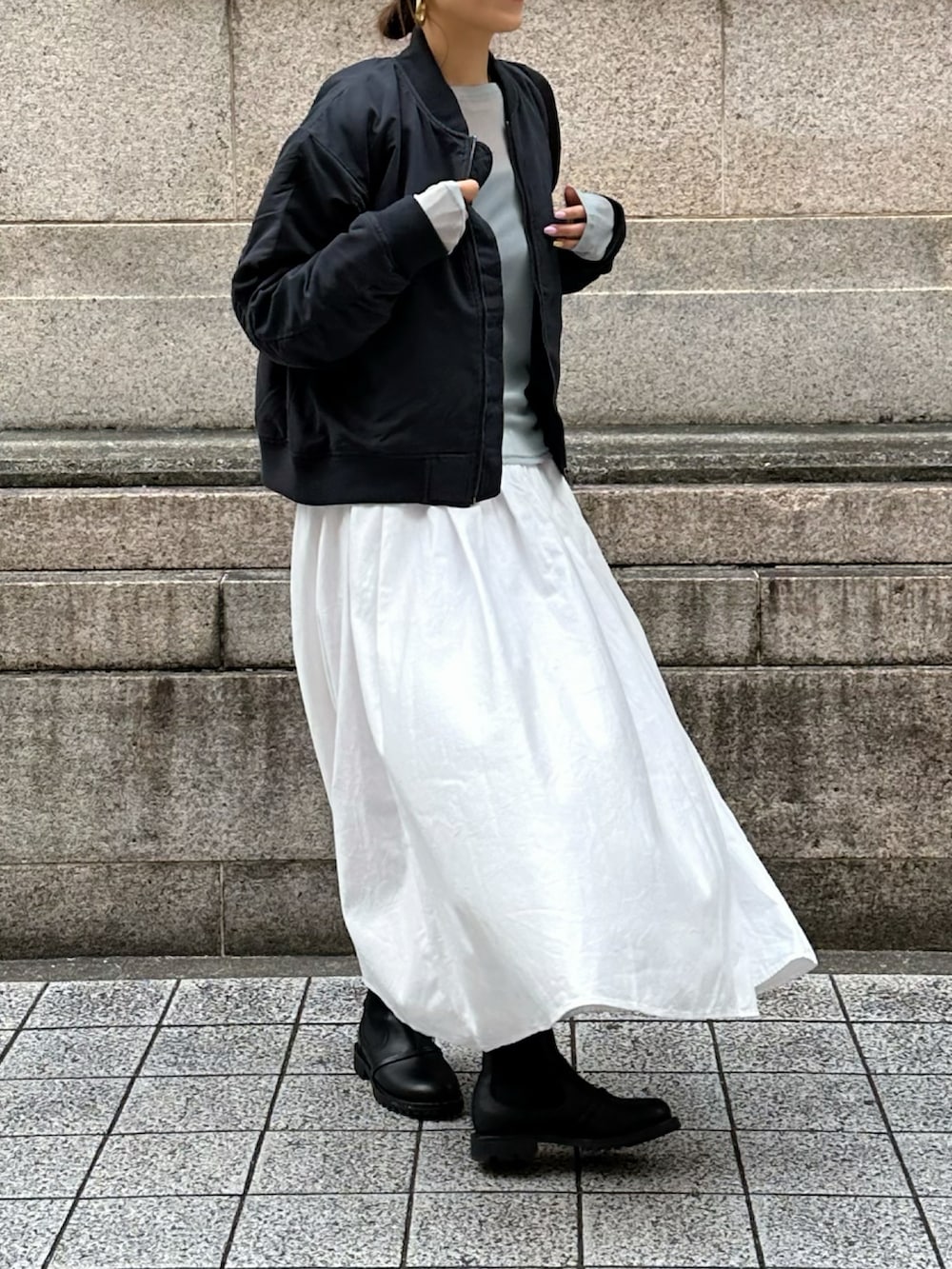 ブラック系のMA-1、ホワイト系のスカートを着用したレディースの冬コーディネートの2枚目の写真