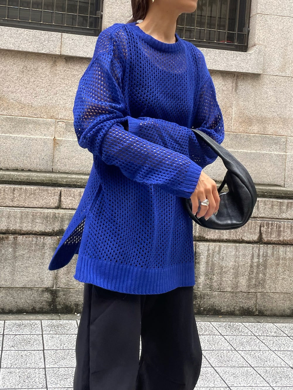 ブルー系のニット/セーター、ブラック系のパンツ、ゴールド系のピアス（両耳用）を着用したレディースの秋コーディネートの2枚目の写真