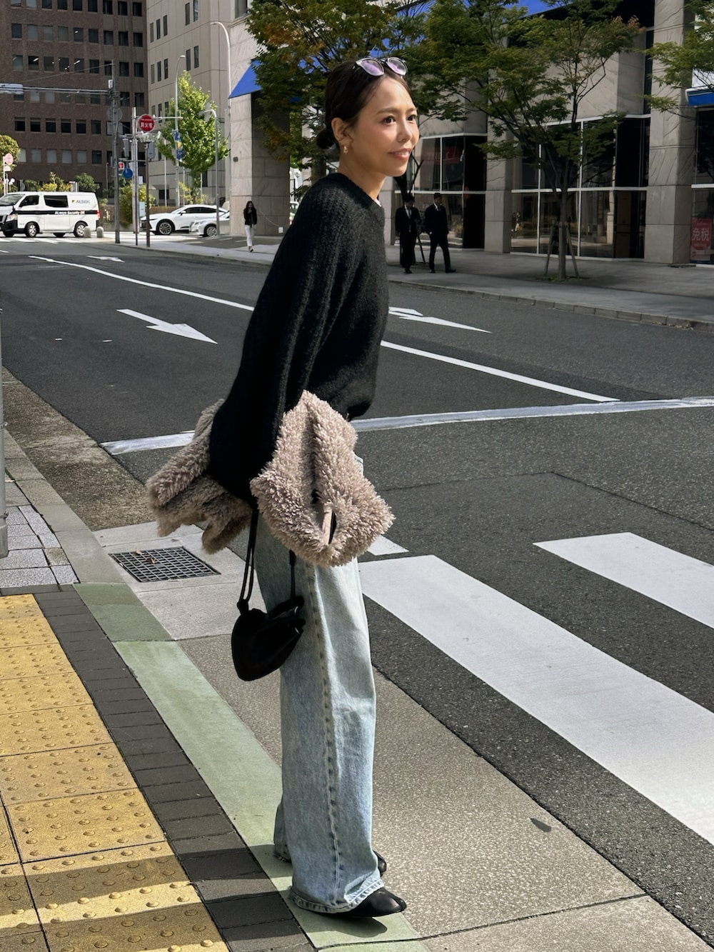 ブラック系のニット/セーター、ブルー系のデニムパンツ、ブラック系のブーツを着用したレディースの秋コーディネートの2枚目の写真