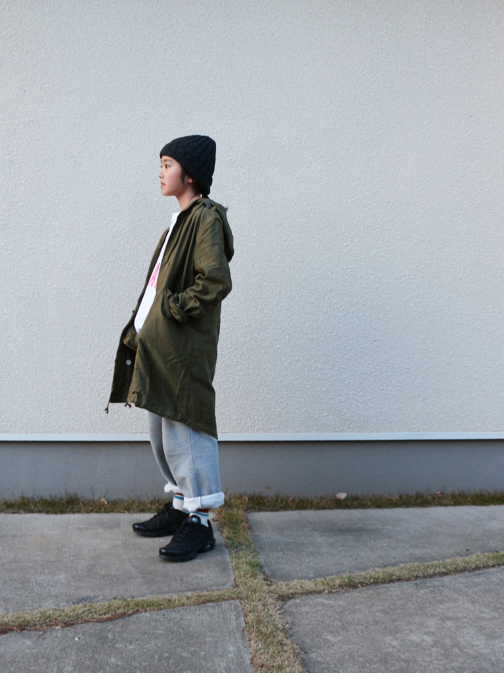 グリーン系のモッズコート、ホワイト系のTシャツ/カットソー、グレー系のスウェットパンツを着用したキッズの春コーディネートの3枚目の写真