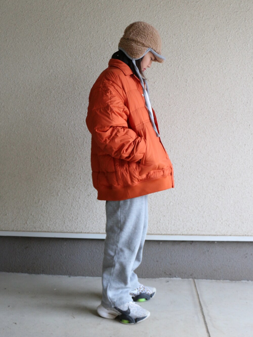 グレー系のスウェットパンツ、オレンジ系のダウンジャケット/コート、ホワイト系のスニーカーを着用したキッズの冬コーディネートの2枚目の写真