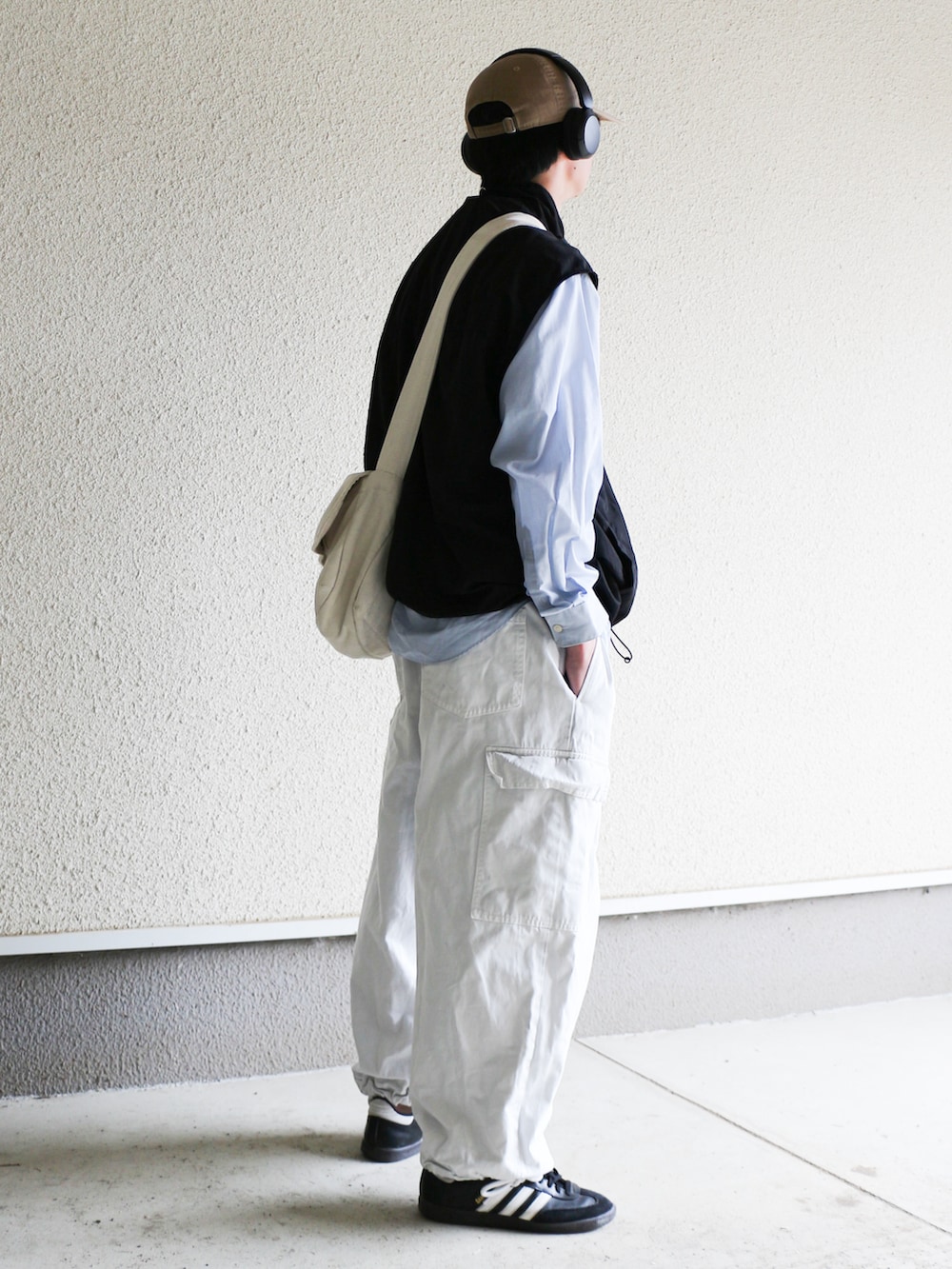 ブラック系のベスト、ホワイト系のカーゴパンツ、ブラック系のスニーカーを着用したメンズの春コーディネートの3枚目の写真