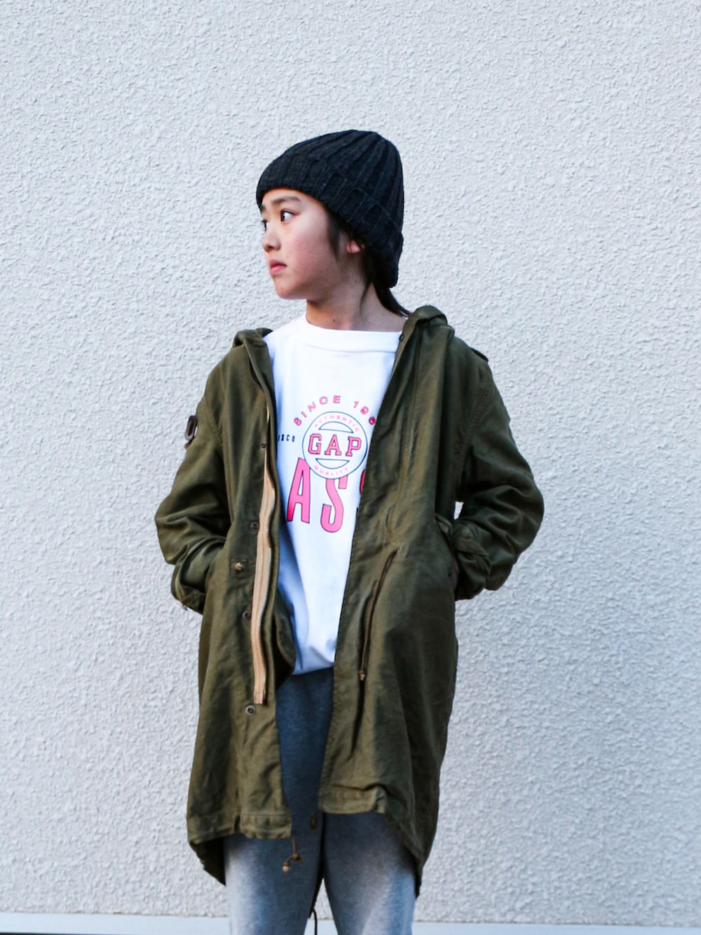 グリーン系のモッズコート、ホワイト系のTシャツ/カットソー、グレー系のスウェットパンツを着用したキッズの春コーディネートの2枚目の写真