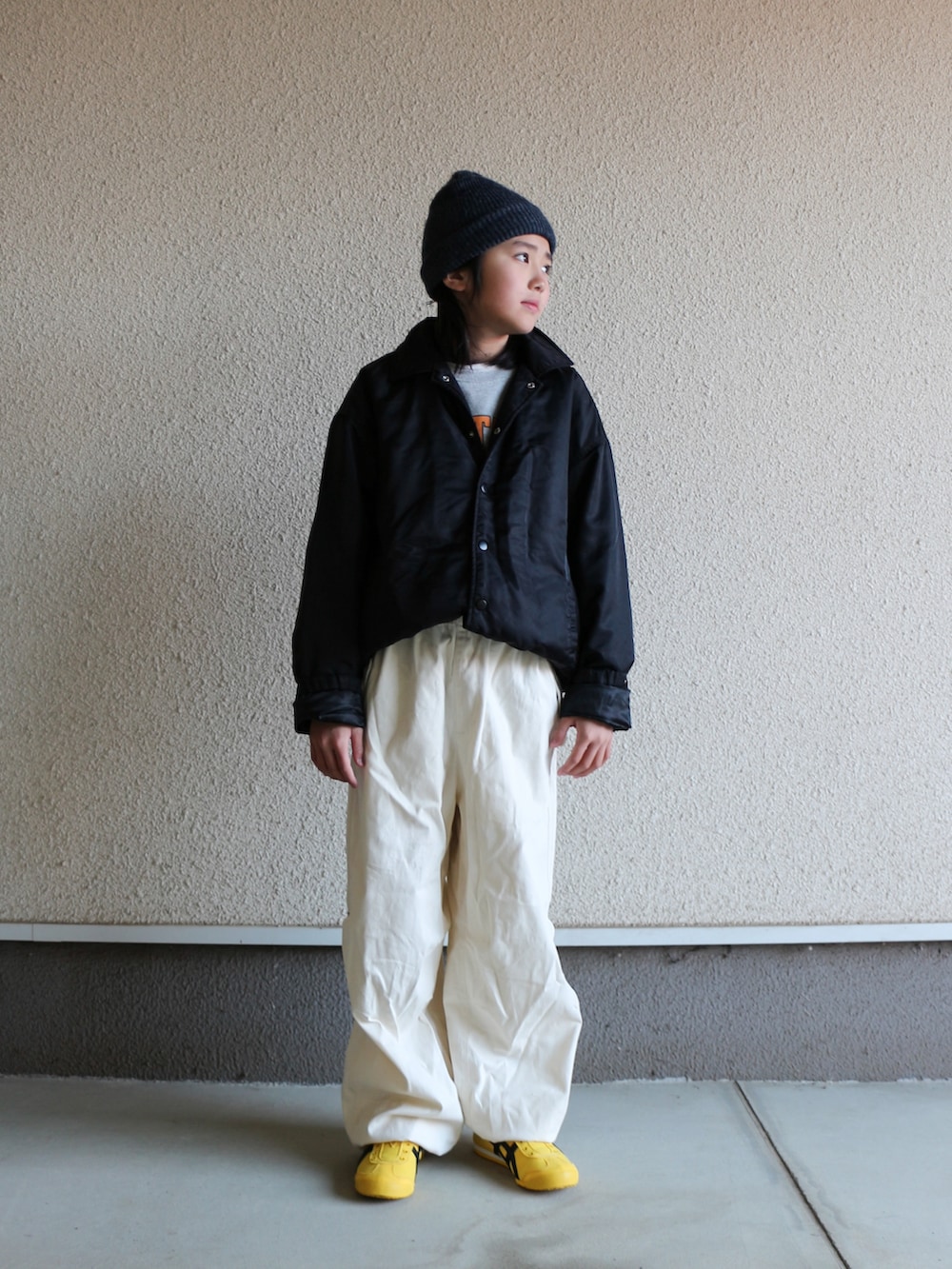 ブラック系のナイロンジャケット、ホワイト系のその他パンツ、イエロー系のスニーカーを着用したキッズの春コーディネートの2枚目の写真