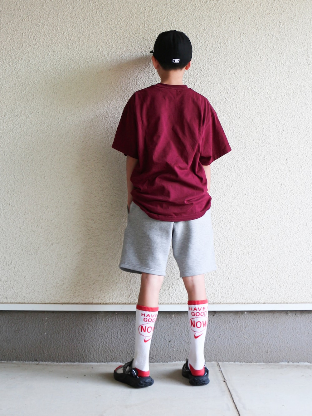 レッド系のTシャツ/カットソー、グレー系のパンツ、ブラック系のサンダルを着用したキッズの春コーディネートの3枚目の写真