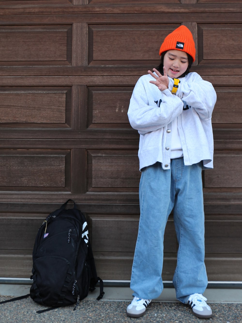 グレー系のカーディガン/ボレロ、ブルー系のデニムパンツ、ホワイト系のスニーカーを着用したキッズの冬コーディネートの2枚目の写真