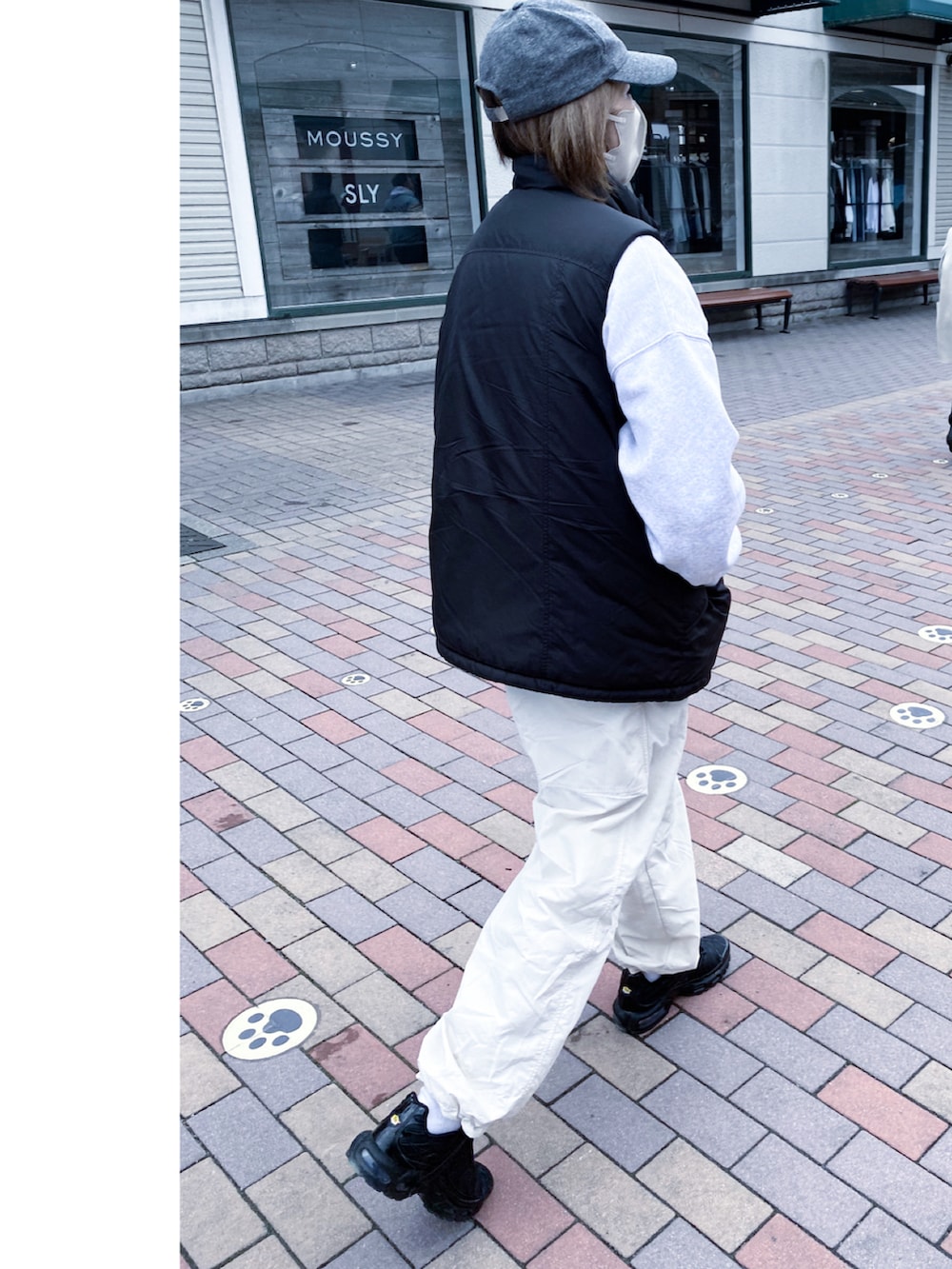 ブラック系のダウンベスト、ホワイト系のカーゴパンツ、ブラック系のスニーカーを着用したレディースの春コーディネートの2枚目の写真