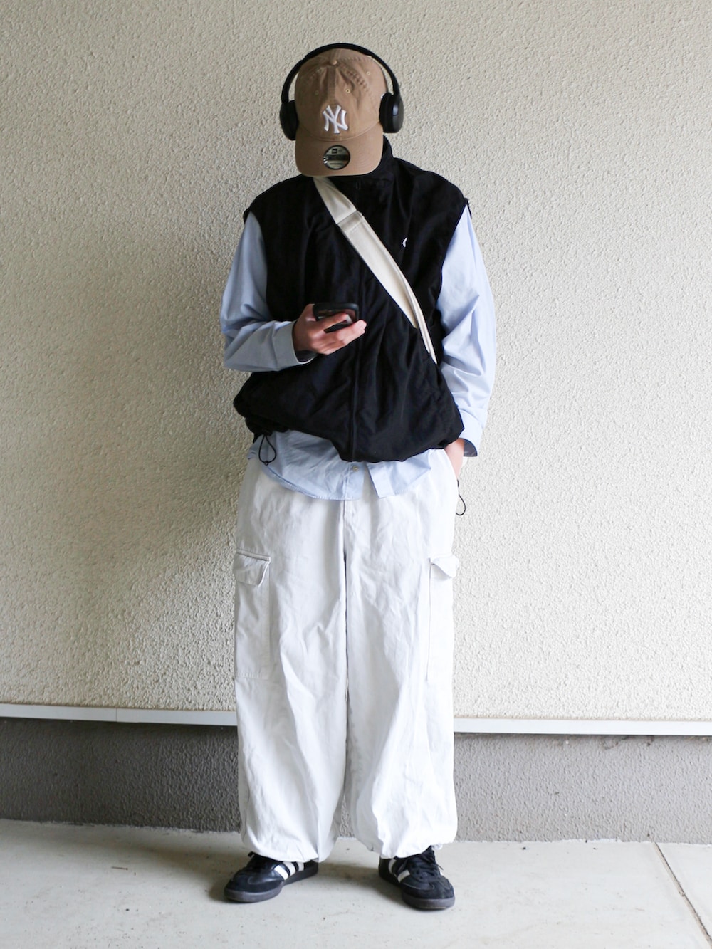 ブラック系のベスト、ホワイト系のカーゴパンツ、ブラック系のスニーカーを着用したメンズの春コーディネートの2枚目の写真