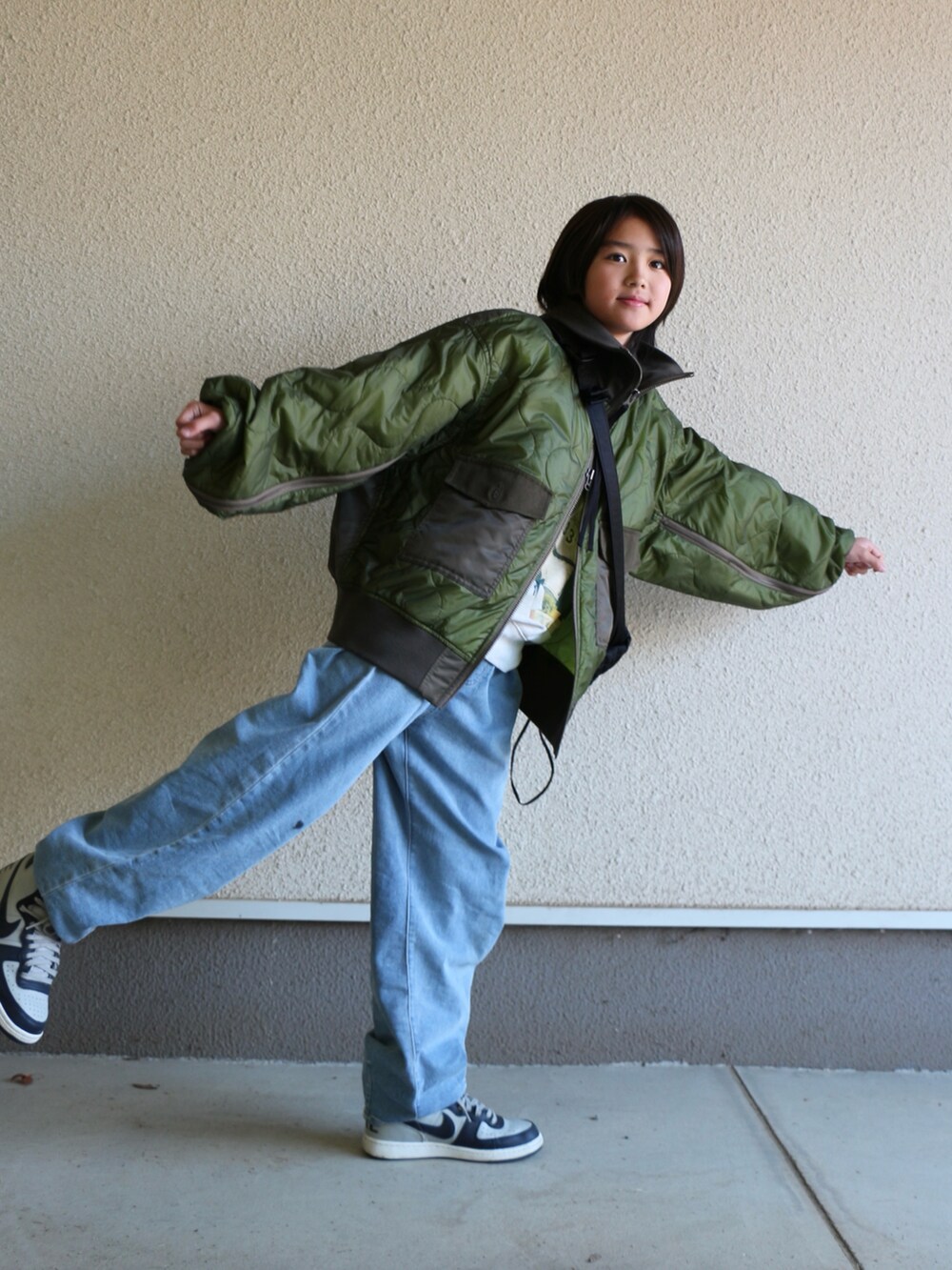 グリーン系のブルゾン、ブルー系のデニムパンツ、グレー系のスニーカーを着用したキッズの冬コーディネートの2枚目の写真