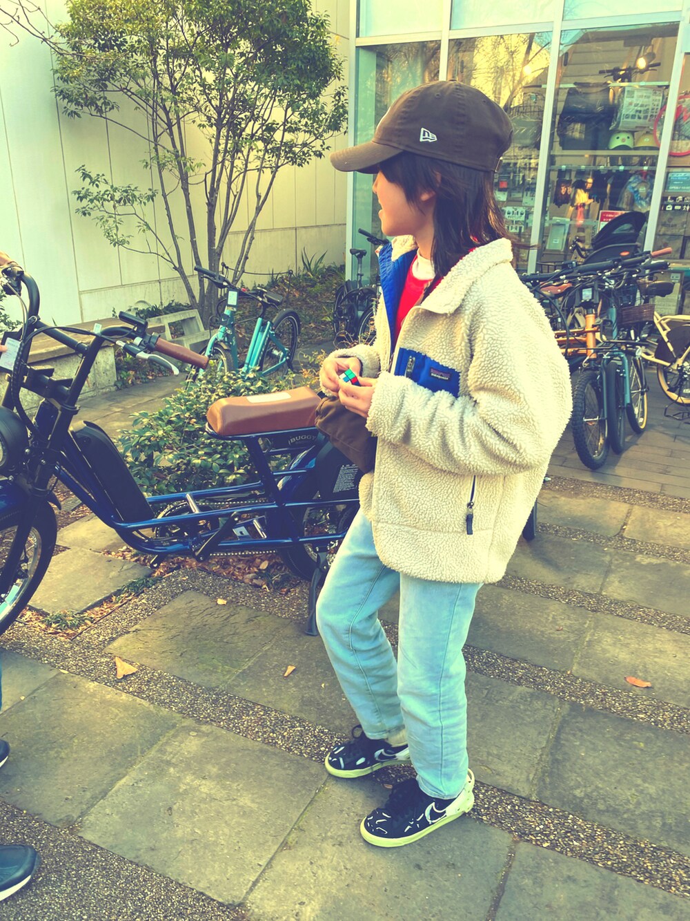 ホワイト系のジャケット/アウター、ブラウン系のショルダーバッグ、ブラック系のスニーカーを着用したキッズの冬コーディネートの2枚目の写真