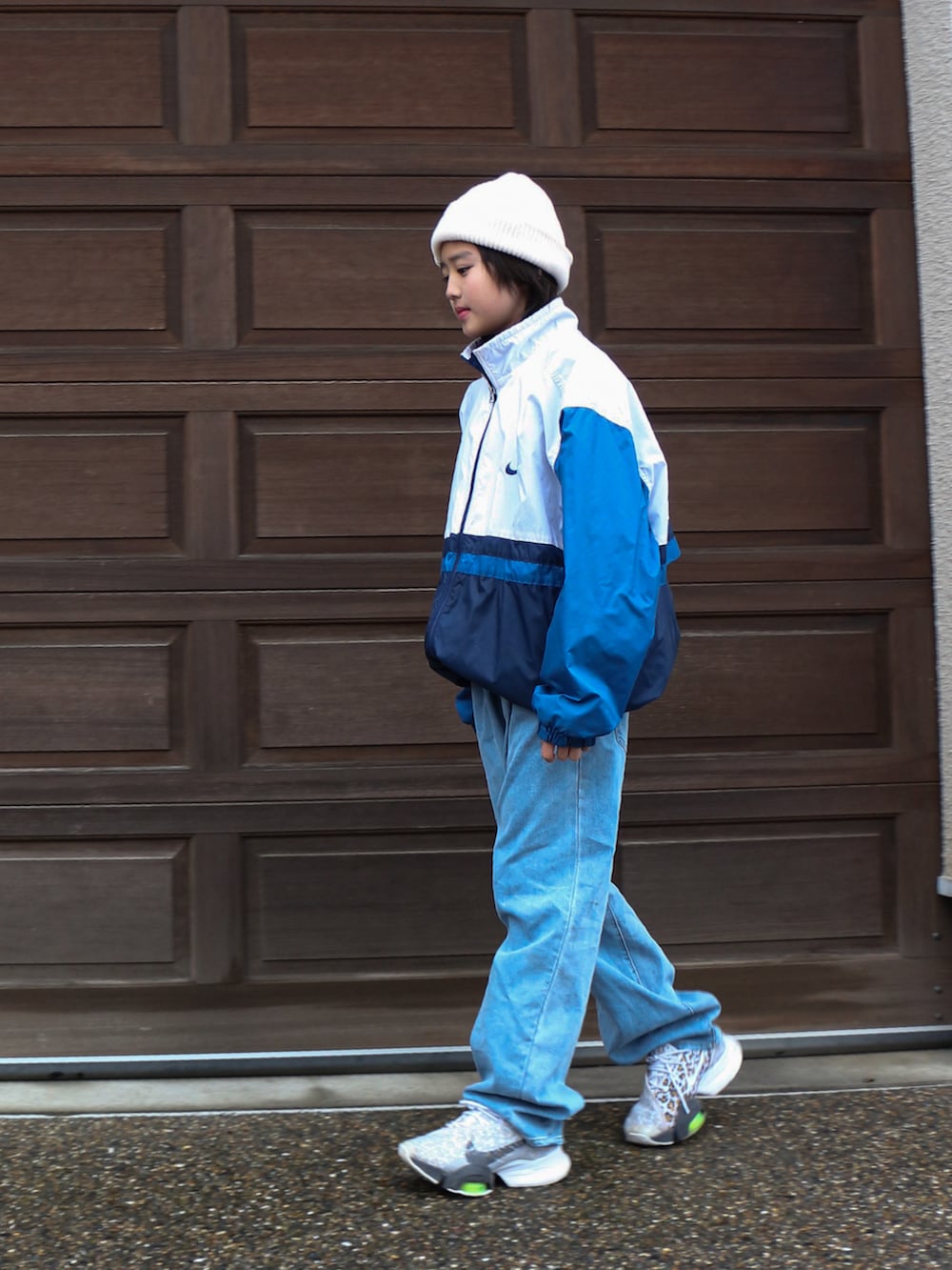 ブルー系のナイロンジャケット、ブルー系のデニムパンツ、ホワイト系のスニーカーを着用したキッズの冬コーディネートの2枚目の写真