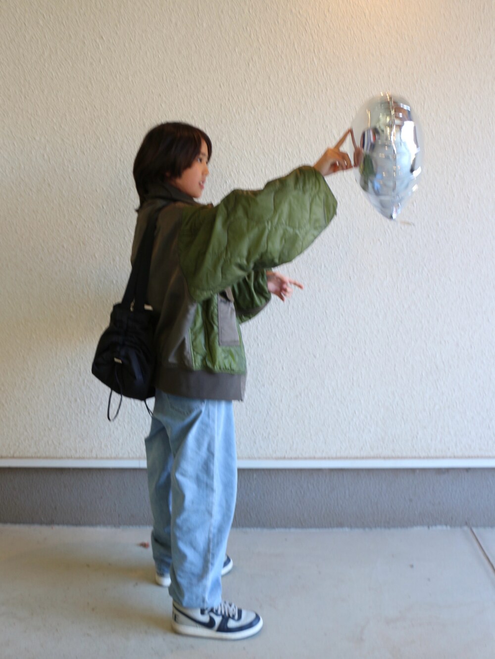 グリーン系のブルゾン、ブルー系のデニムパンツ、グレー系のスニーカーを着用したキッズの冬コーディネートの3枚目の写真