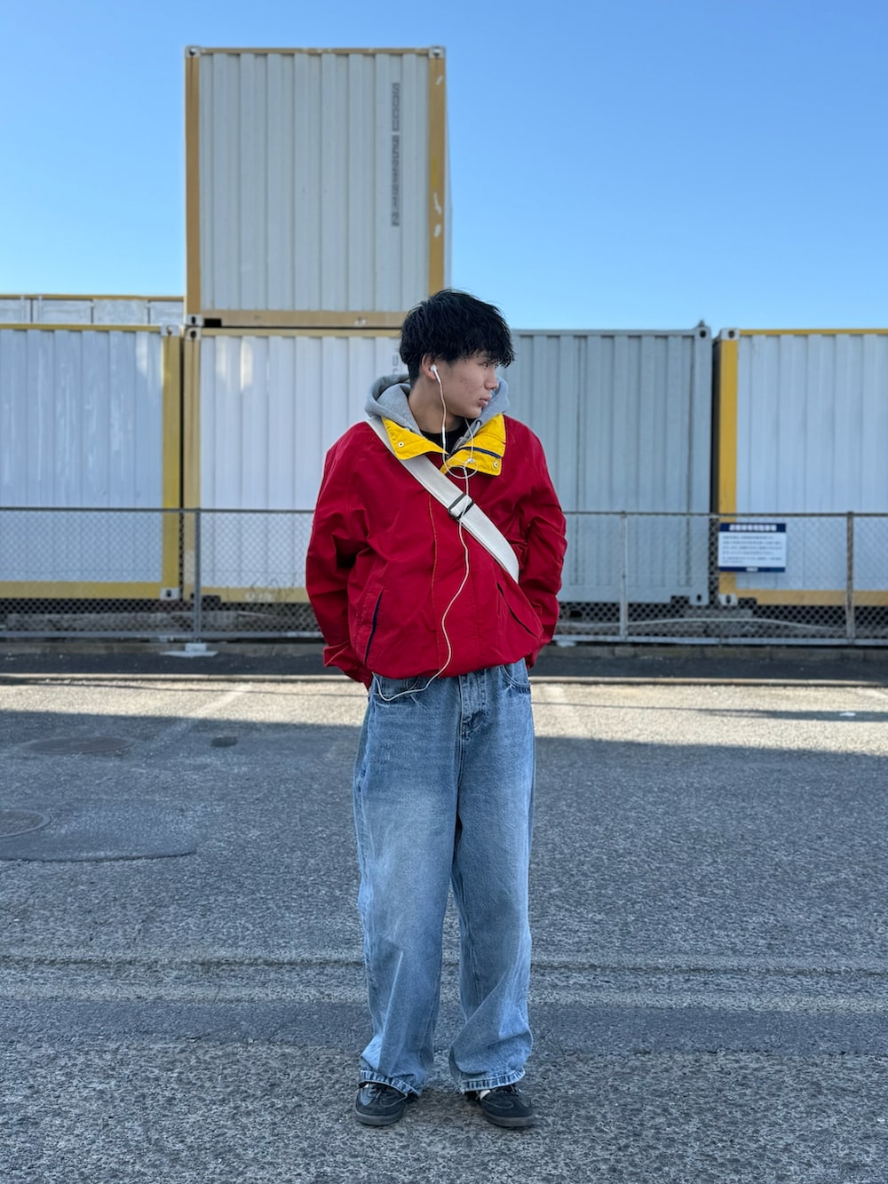 レッド系のブルゾン、ブルー系のデニムパンツ、ブラック系のスニーカーを着用したメンズの冬コーディネートの2枚目の写真