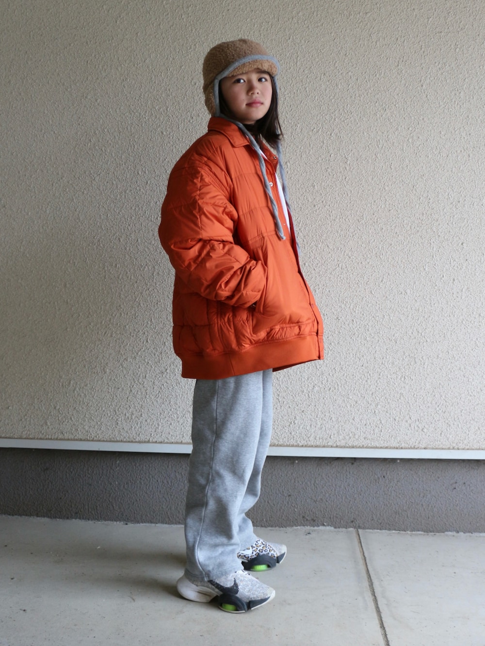 グレー系のスウェットパンツ、オレンジ系のダウンジャケット/コート、ホワイト系のスニーカーを着用したキッズの冬コーディネートの3枚目の写真