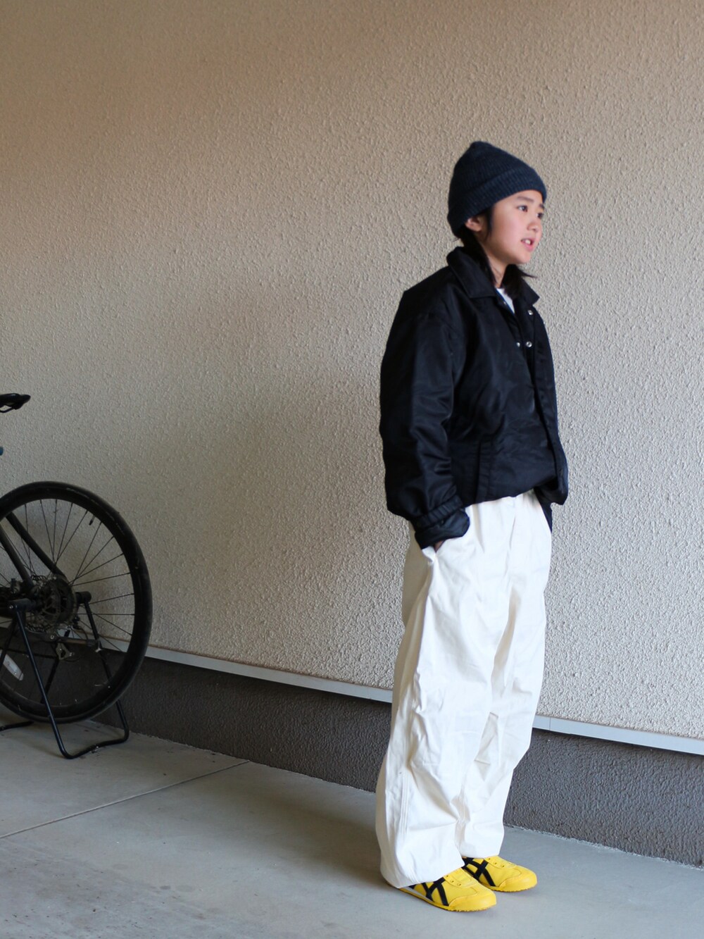 ブラック系のナイロンジャケット、ホワイト系のその他パンツ、イエロー系のスニーカーを着用したキッズの春コーディネートの3枚目の写真