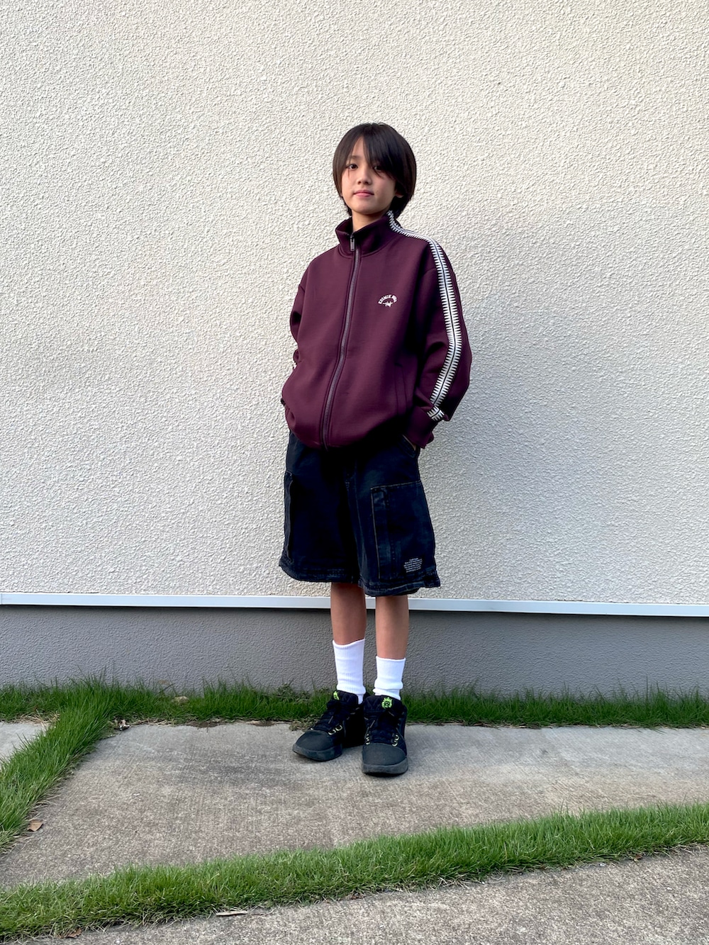 ブラック系のカーゴパンツ、レッド系のその他アウター、ブラック系のスニーカーを着用したキッズの秋コーディネートの2枚目の写真