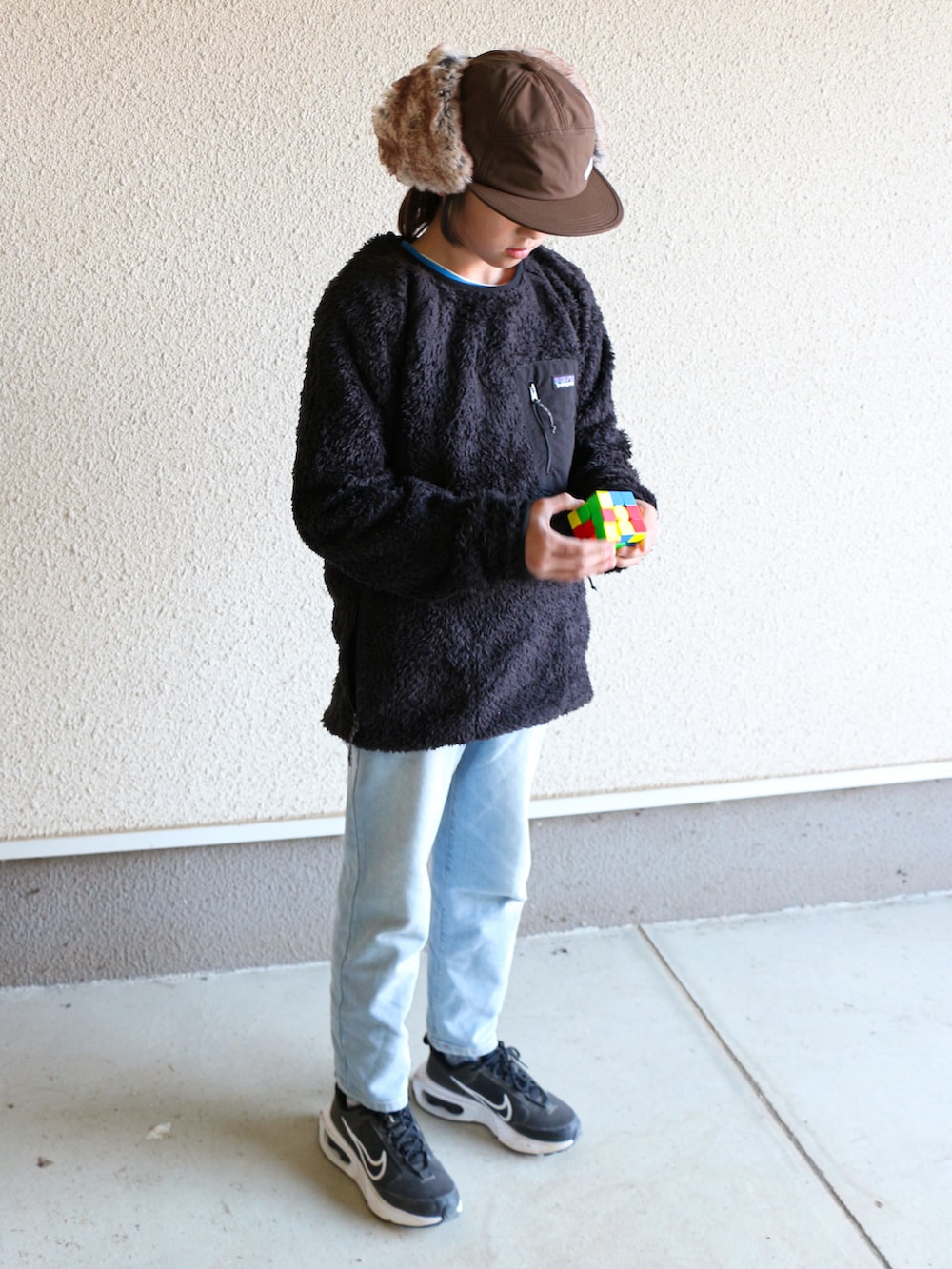 ブラック系のジャケット/アウター、ブラック系のスニーカー、ブラウン系のキャップを着用したキッズの秋コーディネートの2枚目の写真